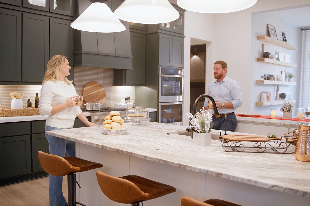 A couple talking across a kitchen island set with pastries and holiday decor