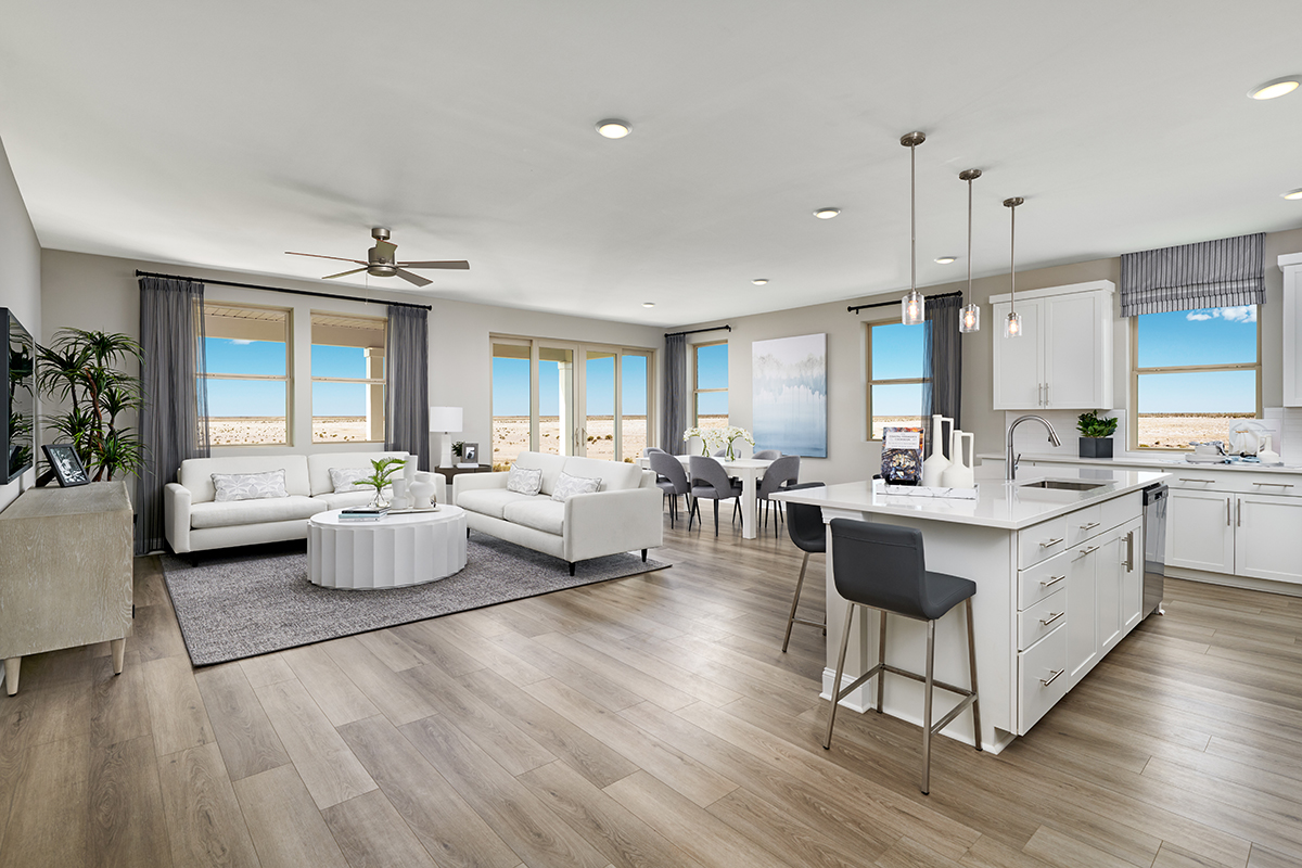 An open living, dining, and kitchen with sofas, a dining table, and a kitchen island