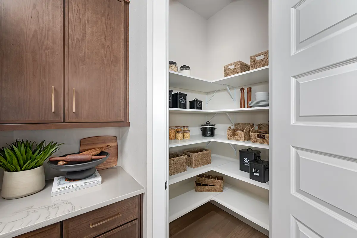 A walk-in pantry with open shelves, baskets, and cabinetry